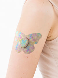 Dexcom G7 adhesive patch, butterfly shape, on the arm, close-up
