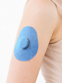 Dexcom G7 adhesive patch, drop shape, on the arm, close-up