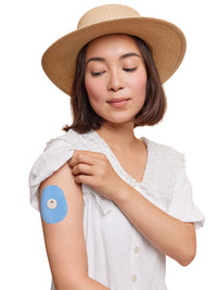 FreeStyle Libre 3 adhesive patch, drop shape, worn on a woman's arm