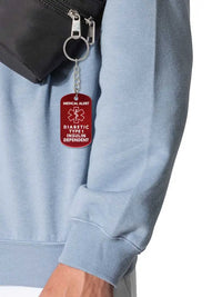 Diabetic Type 1 insulin dependent metal keychain with red medical alert symbol hanging from a bag zipper.